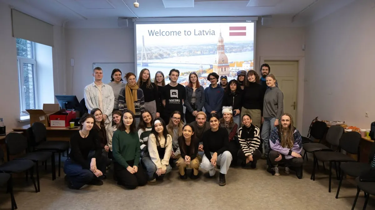 Group photo of exchange students in front of a screen reading “Welcome to Latvia”.