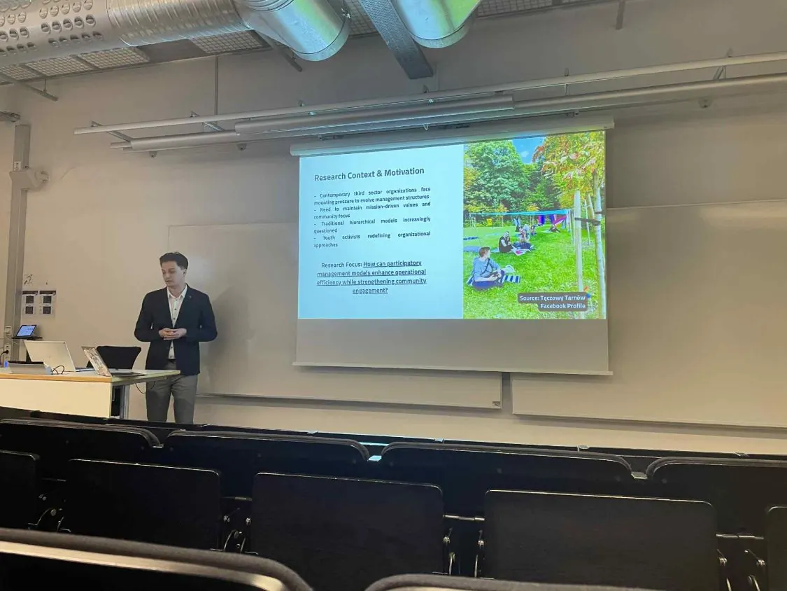 Artur Sendyka next to a screen showing the slide “Research Context & Motivation” on management in third-sector organizations.