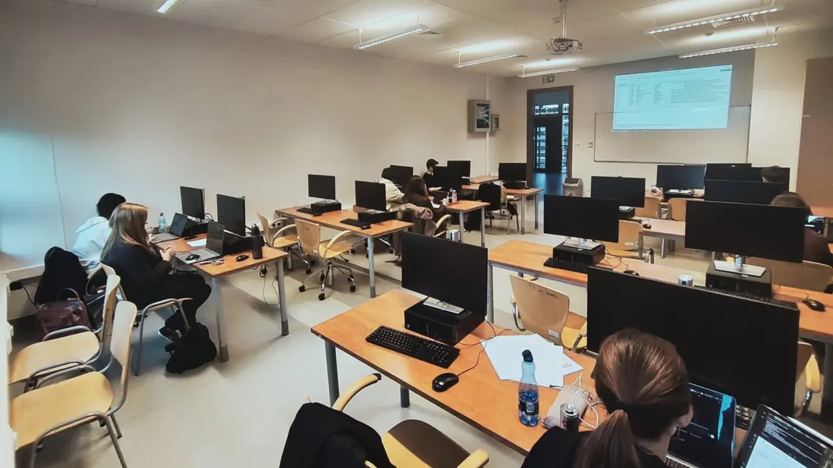 Workshop participants at computers in a lab, with a table shown on the projector screen.